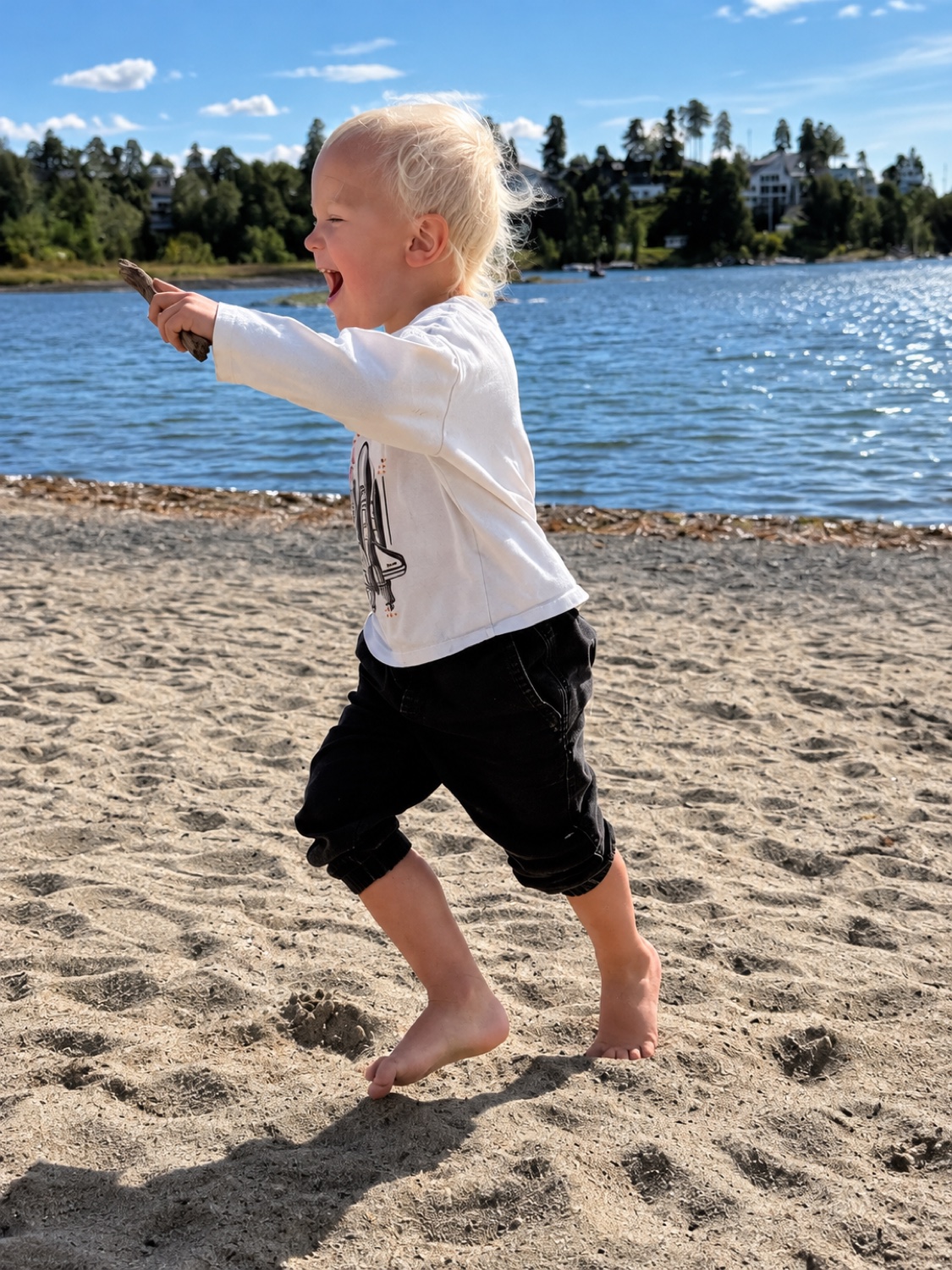 En glad gutt i bevegelse på stranden